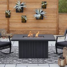 an outdoor fire pit with two chairs and a table in front of it on a patio