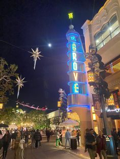 people are walking down the street in front of a tower that says believe above it