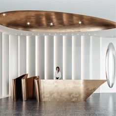 a woman sitting behind a counter in a room with white walls and gold circles on the ceiling