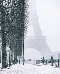 the eiffel tower is covered in snow as people walk by on a snowy day