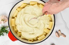 a person is spooning sauce over some pasta in a skillet on a table