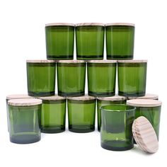 many green glass cups with lids are stacked up on top of each other and one has a wooden lid