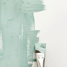 a paintbrush sitting on top of a white table next to a wall with green paint