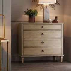 a wooden dresser sitting next to a wall with a lamp on it's side