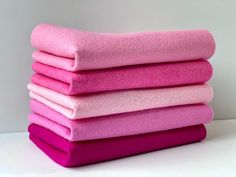 a stack of pink towels sitting on top of a white table next to each other