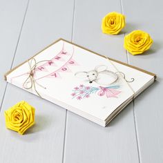 a greeting card with yellow flowers and ribbon on the side, next to it is a pair of scissors