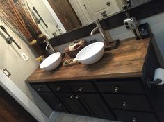 two white bowls sit on top of a wooden counter in front of a bathroom mirror