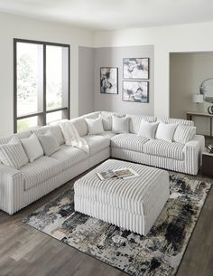 a living room with a large white sectional couch and ottoman in front of a window