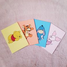 four different winnie the pooh cards on a pink blanket