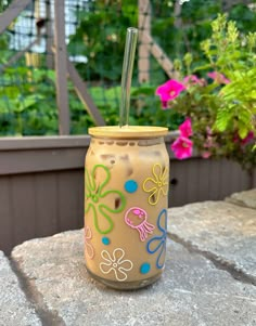 a glass with a straw in it sitting on top of a stone table next to flowers