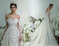 a woman in a wedding dress standing next to a white flower arrangement and wearing a tiara