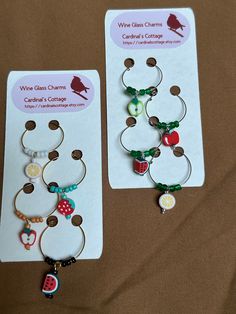 two wine glass charms are on display in front of a card that says wine glass charms cambridge's college