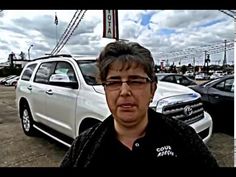 a woman standing in front of a parking lot filled with parked cars and looking at the camera