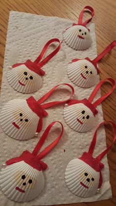 four seashells with red ribbon on them are sitting on a piece of paper