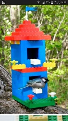 a bird house made out of legos sitting on top of a rock in the woods