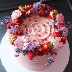 a cake decorated with flowers and strawberries on a plate