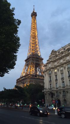 the eiffel tower lit up at night in paris, france with cars passing by