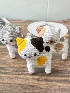 three small crocheted cats sitting on top of a wooden table