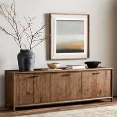 a wooden cabinet with two vases sitting on top of it next to a painting