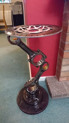 a table that has some kind of metal object on it's stand in front of a red wall