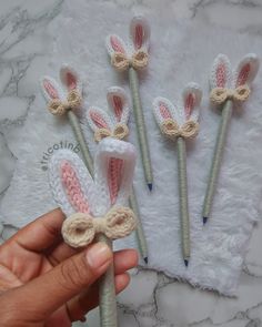 three crocheted bunny ears are being held by a person's hand on a white towel