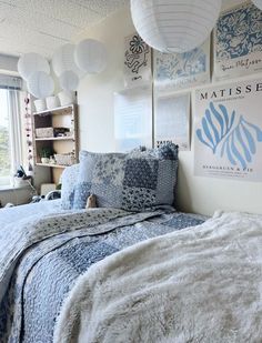 a bed room with a neatly made bed and lots of pictures on the wall above it