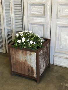 a planter with white flowers sitting in front of a door