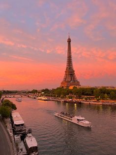 the eiffel tower towering over the city of paris at sunset with boats in the river below