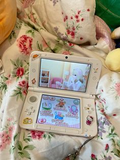 an open nintendo wii game system sitting on top of a bed next to stuffed animals