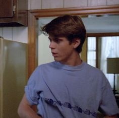 a young man standing in front of a refrigerator with his hands on his hips and looking off to the side