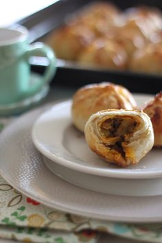 two pastries on a plate next to a cup and saucer