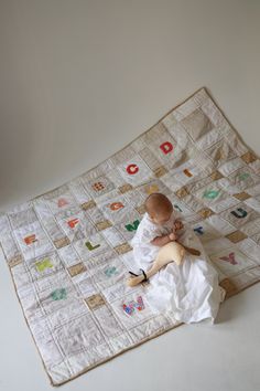 a baby sitting on top of a white blanket with letters all over the placemat