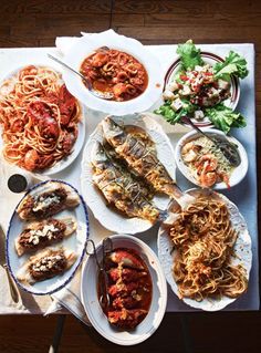 a table topped with plates of food and bowls of sauces on top of it