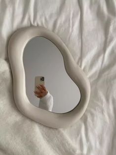 a person taking a selfie in front of a heart shaped mirror on a bed