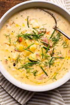 a white bowl filled with potato soup on top of a striped napkin next to a spoon