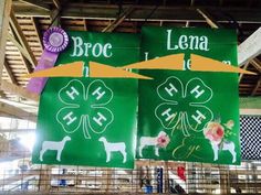 two green banners hanging from the ceiling in a building with sheep and flowers on them