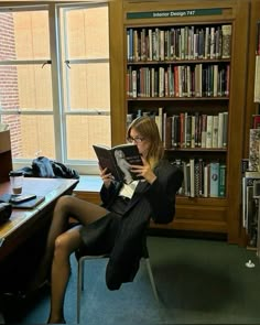 a woman sitting on a chair reading a book in front of a library full of books