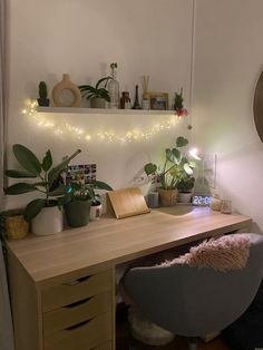 a wooden desk topped with plants next to a window covered in fairy lights and a clock