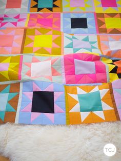 a colorful quilt is laying on top of a white rug