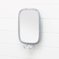 a bathroom mirror mounted to the side of a white wall next to a tiled wall