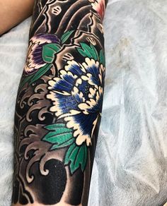 a person laying on a bed with a tattoo on their arm and leg, covered in flowers