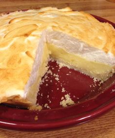 a pie with one slice cut out on a red plate, sitting on a wooden table