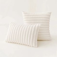 several white pillows stacked on top of each other in front of a white wall and floor