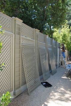 a person standing on a ladder next to a wall with latticed panels in it