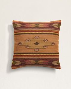 an orange and brown pillow on a white wall