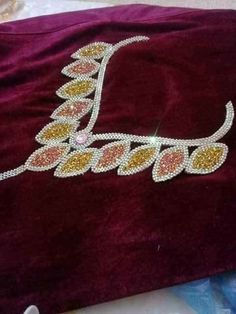 a red velvet bag with gold and white beads on it's side, sitting on top of a table