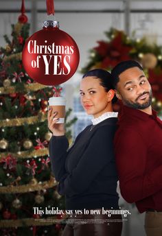 a man and woman standing in front of a christmas tree