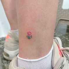 a small pink flower tattoo on the ankle