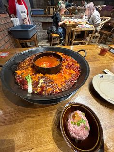 a table topped with lots of food on top of a wooden table covered in plates and bowls