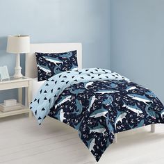 a bed with blue and white comforters in a room next to a night sky